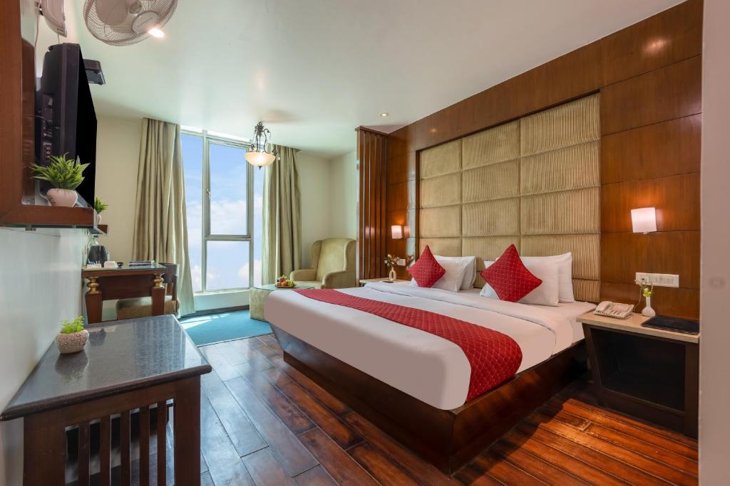 a hotel room with a large bed with red pillows at Hotel Aura - 05 Mins from New Delhi Railway Station & Connaught Place in New Delhi