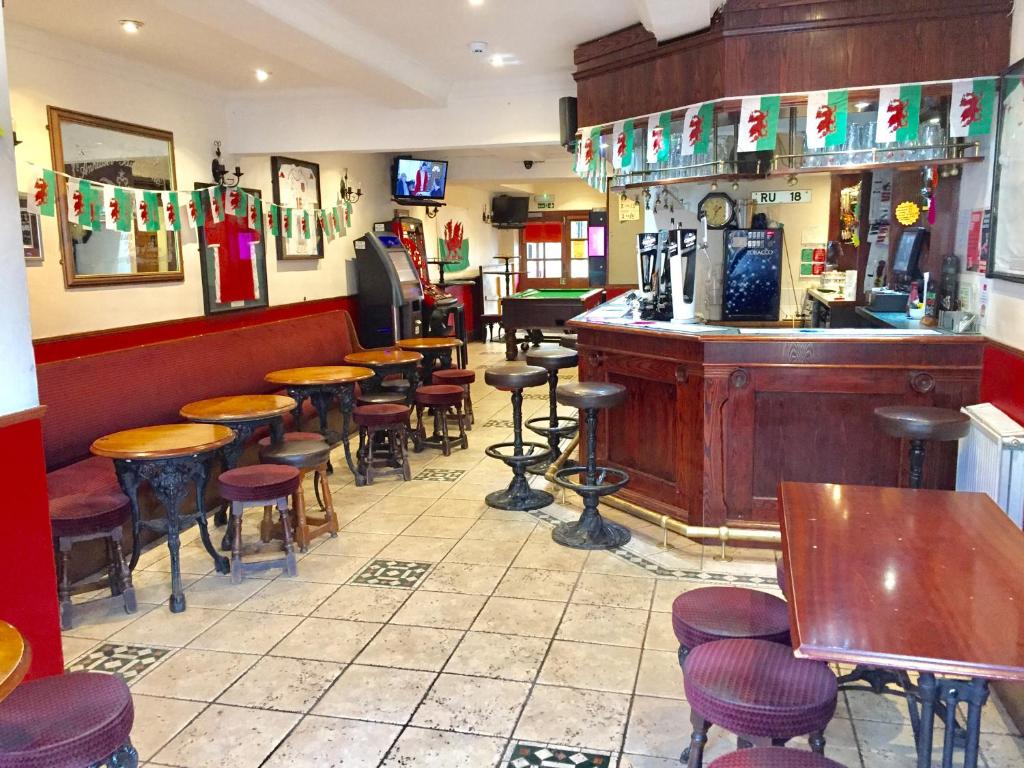 - un bar avec des tables et des tabourets en bois dans un restaurant dans l'établissement Plas Coch Hotel Ltd, à Bala
