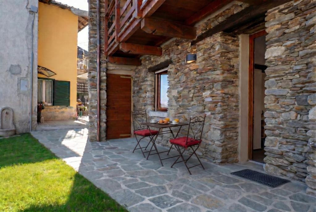 a patio with a table and chairs in a stone building at Ca da Smarè - Where Time stands Still in Someraro