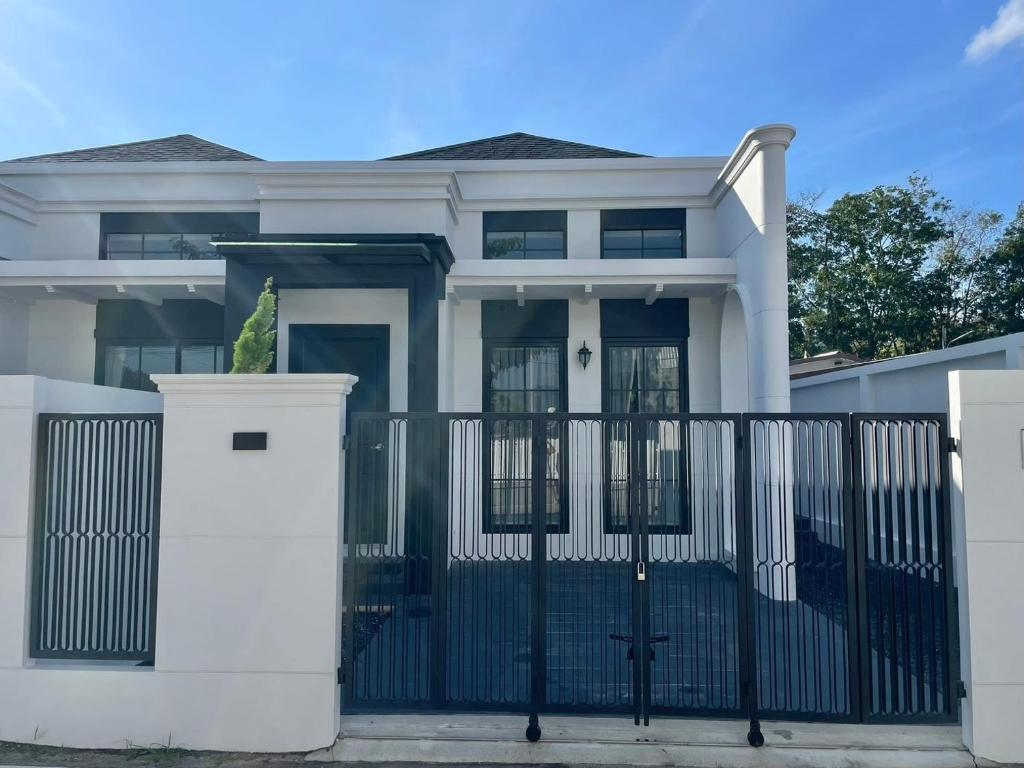 a white house with a black gate at La Casa Bella in Ban Nong Chaeng