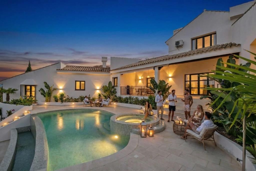a group of people standing around a swimming pool in a house at Villa Kahuna Sotogrande in Sotogrande