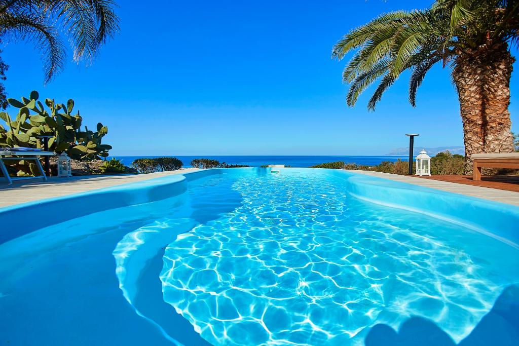a swimming pool with a palm tree in the background at Villa Gabbiano - Scopello-Villas in Scopello