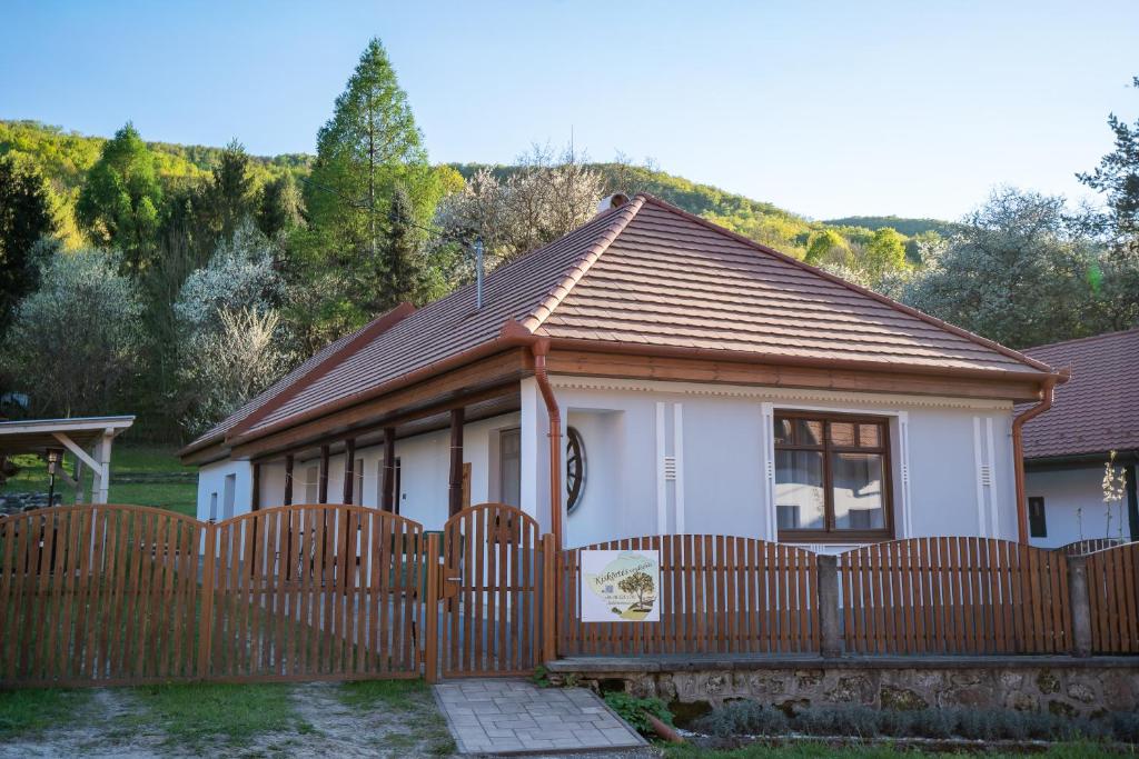 a small white house with a wooden fence at Kiskörtés Vendégház Óhuta in Háromhuta