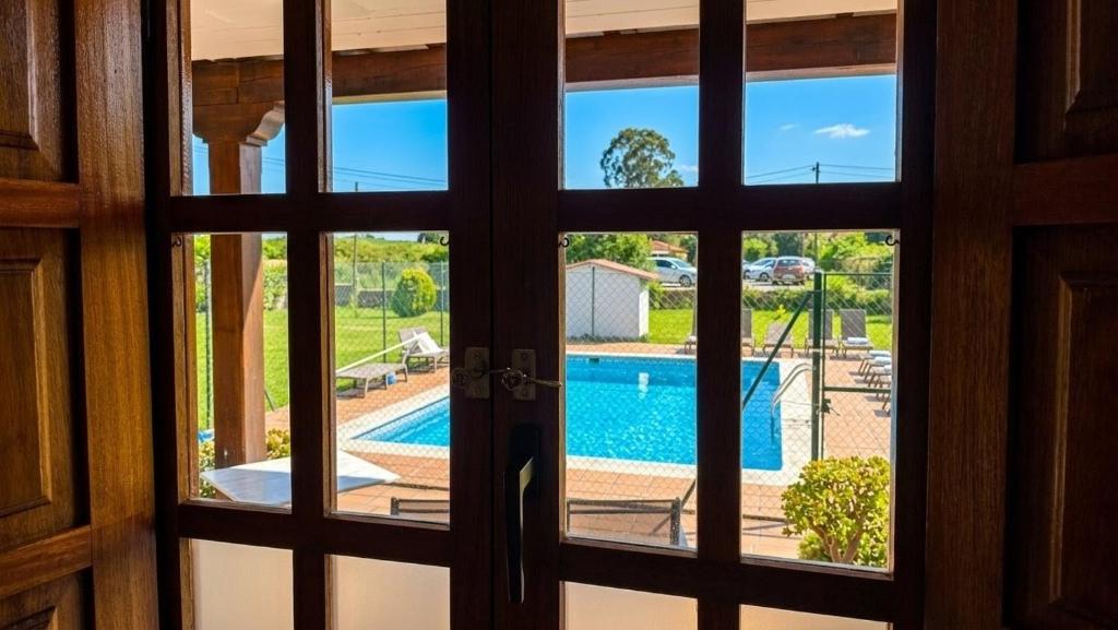 a door looking out at a swimming pool through a window at Posada Adela in Santillana del Mar