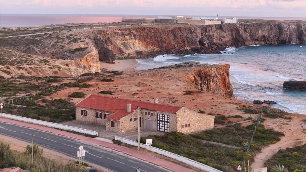 a building on the side of a road next to the ocean at Casa dos Rebolinhos in Sagres