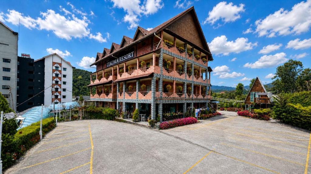 a large building in a parking lot in front of a building at Tekoma Hotel & Hostel Cameron Highlands - FREE SHUTTLE SERVICE in Tanah Rata