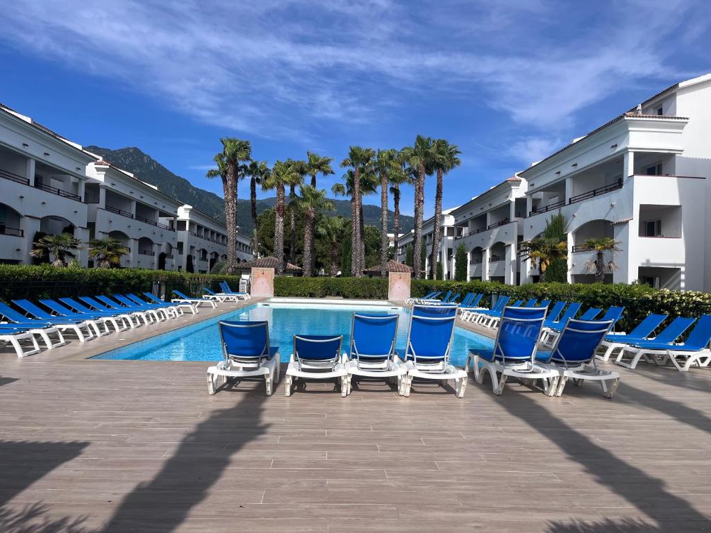 a row of blue lounge chairs next to a swimming pool at APPARTEMENT sognu di rena G1 in San-Nicolao