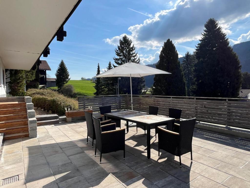a table with chairs and an umbrella on a patio at Ferienwohnung Heid in Rettenberg