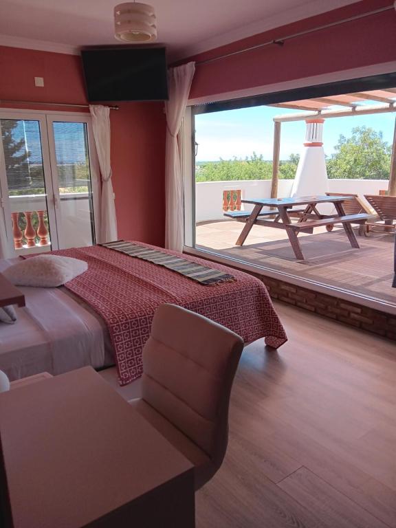 a bedroom with a bed and a table and a large window at Alojamento local Patudos, Suite com terraço privado in Tavira