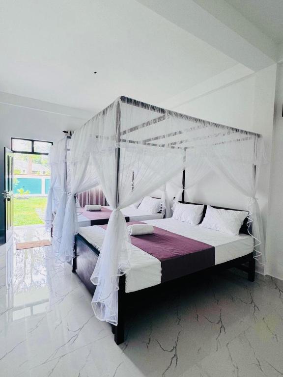 a bed with a canopy in a white room at Hotel Elysian in Udawalawe