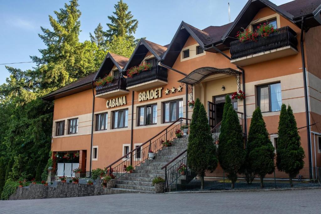 a building with stairs and trees in front of it at Pensiune Cabana Bradet in Şimleu Silvaniei