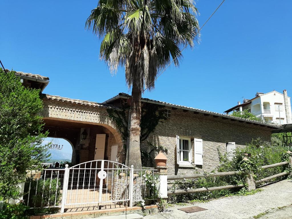 a palm tree in front of a building with a gate at Guesthouses Thomas & Cato in Vátos