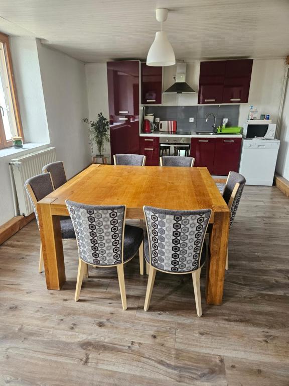 a wooden dining room table with chairs and a kitchen at relais de la diligence in Morteau