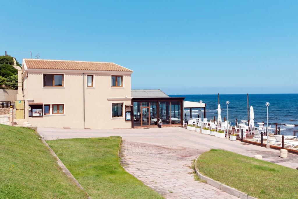 a building on the beach with the ocean in the background at La Locanda del Mare in Codaruina