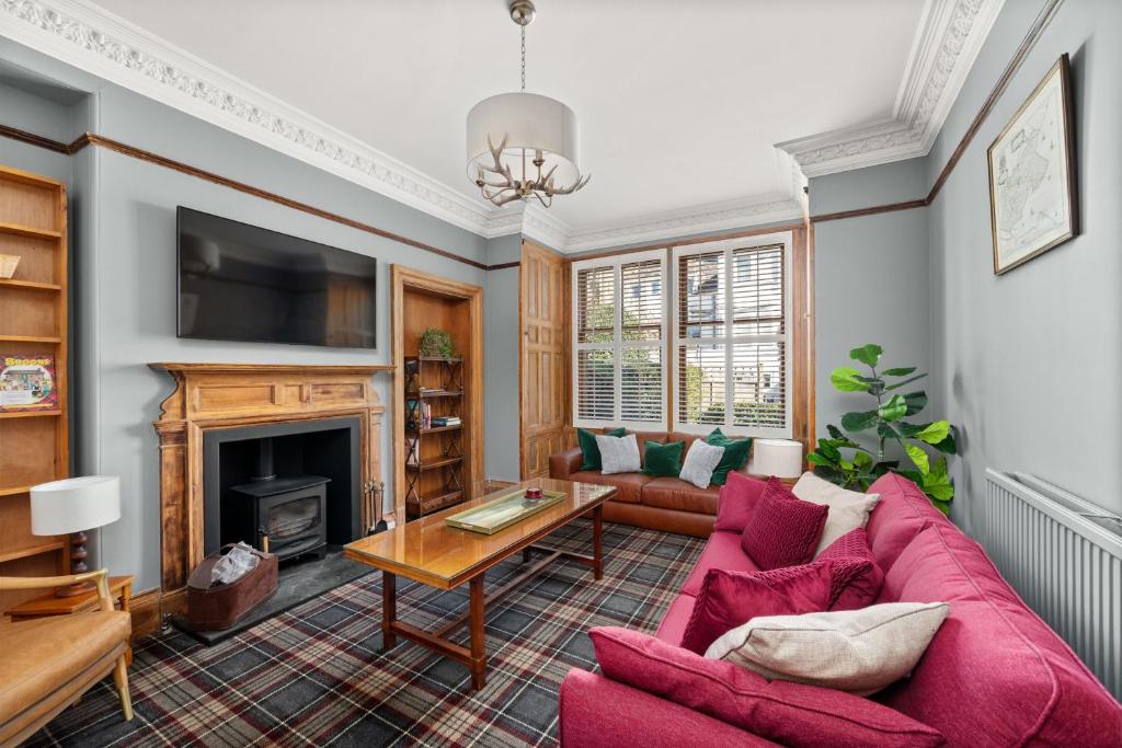 a living room with a red couch and a fireplace at Heywood Cottage in St. Andrews