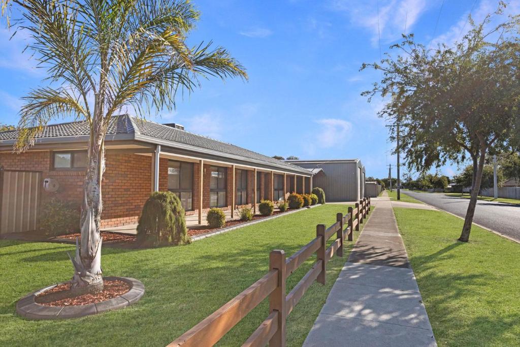 a house with a palm tree next to a fence at Maffra Retreat in Maffra