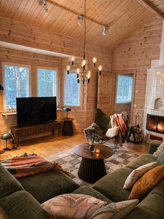 a living room with a couch and a tv at Holiday Cabin Naalinpesä incl Wifi, outdoor jacuzzi for extra fee in Äkäslompolo