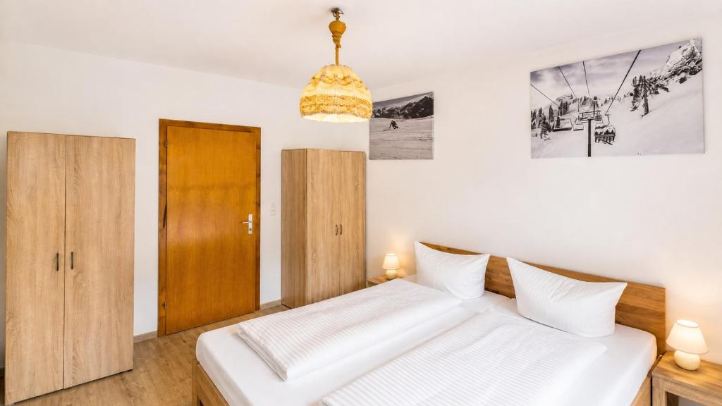 a bedroom with a white bed and a wooden door at Basic Work Stay Rooms - Highspeed WiFi - Easy Self Check-In - Practical and Affordable Stay in Bürs