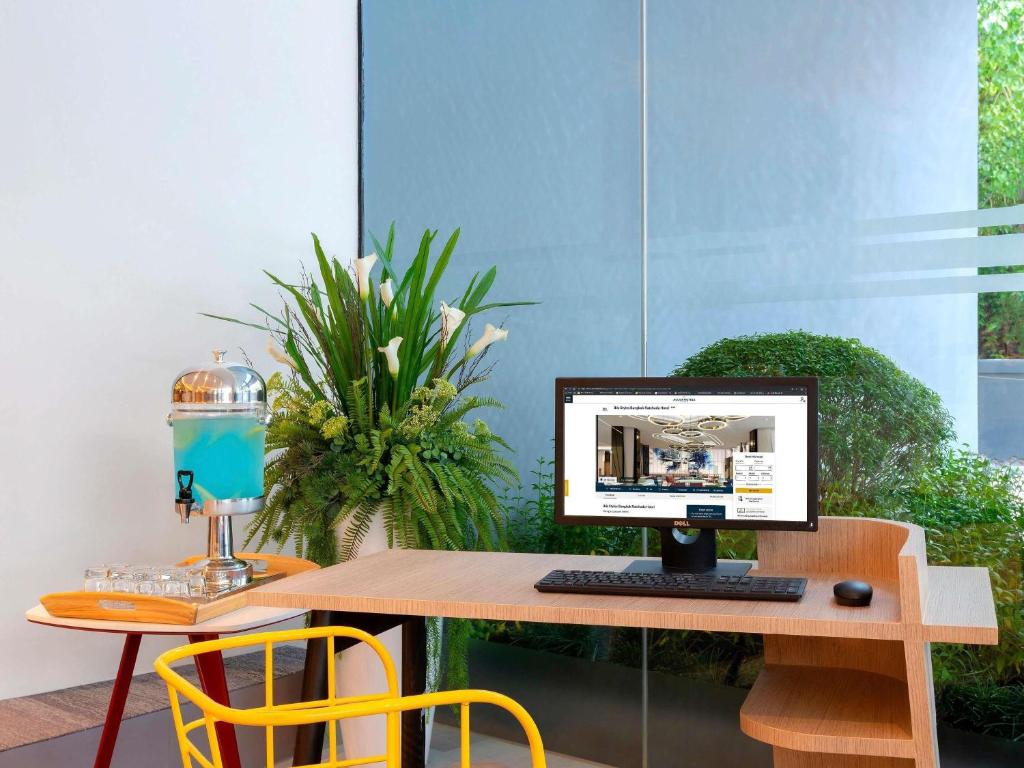A compact computer workstation beside a window and indoor plants.