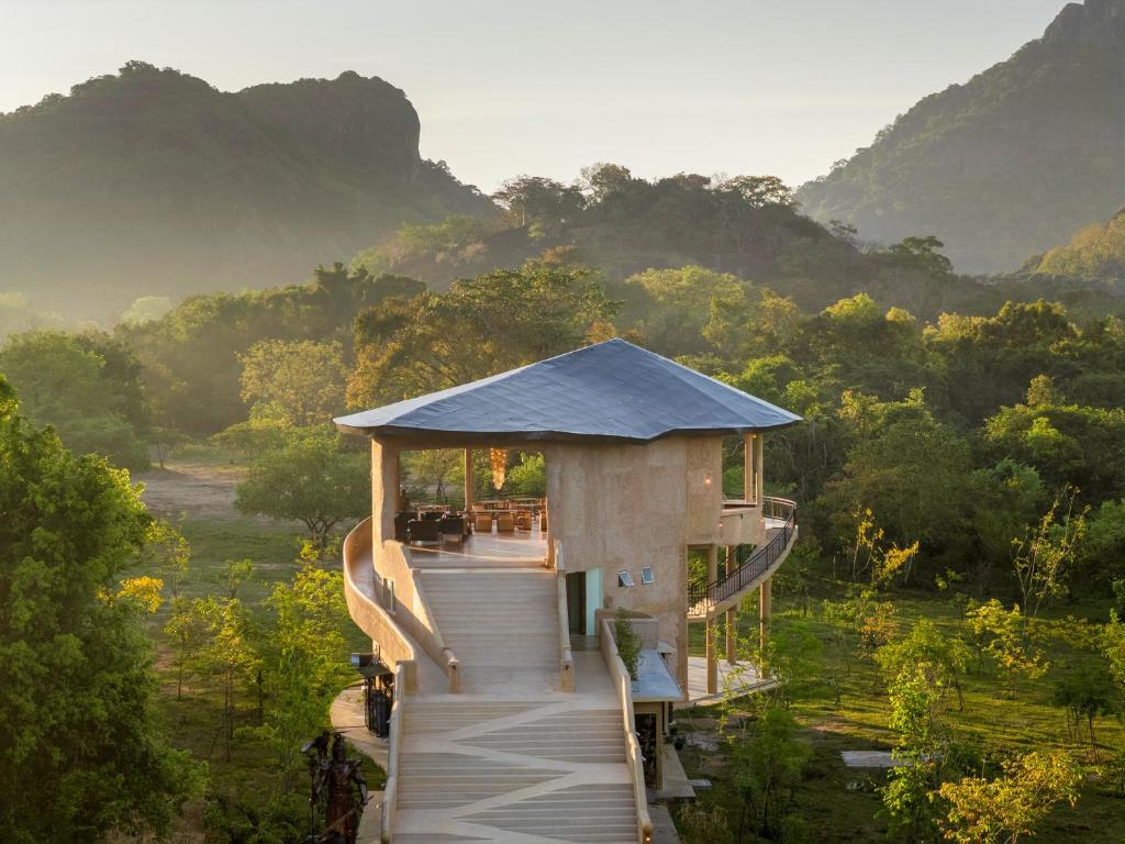 a house with a roof on top of a field at AARAWILD Luxury Villas - Sigiriya in Sigiriya