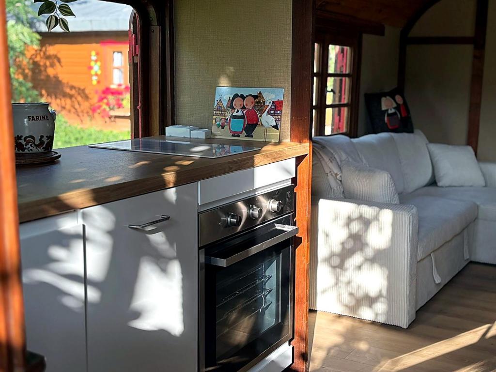 a kitchen with a stove top oven in a living room at Relais Équestre du Neufeld - Roulotte Nature in Oberhaslach