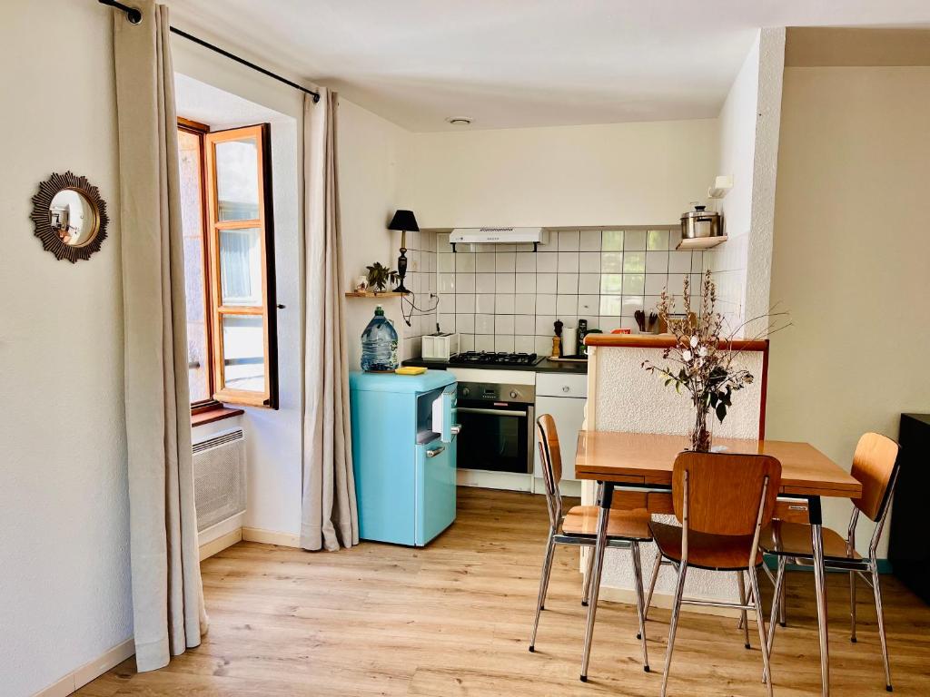 a kitchen with a table and a blue refrigerator at Appartement minimaliste et cozy in Cajarc