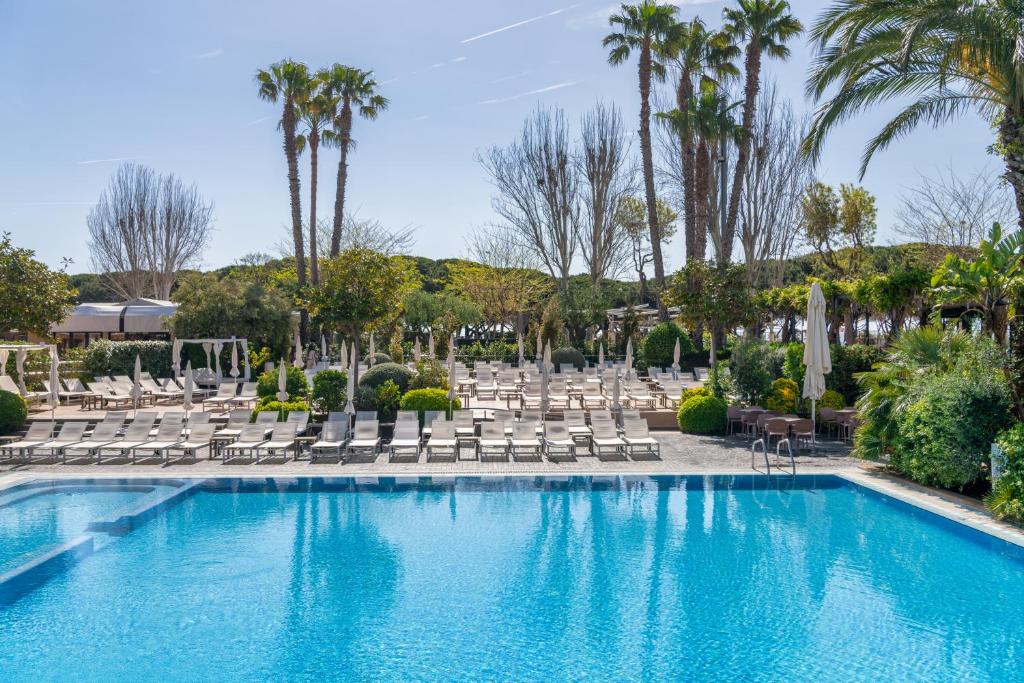 a swimming pool with lounge chairs and palm trees at AQUA Hotel Onabrava & Spa 4*Sup in Santa Susanna