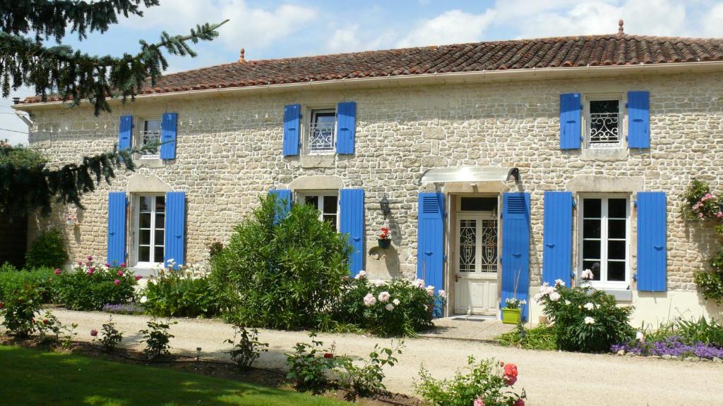 Maison en pierre avec volets bleus et fleurs dans l'établissement Le Clos de la Vigne, à Montreuil