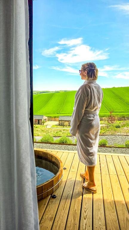 a woman standing on a deck looking out of a hot tub at Ostara Ecolodge in Saint-Mards-en-Othe