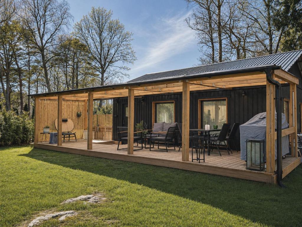 a wooden house with a deck in a yard at Ljungskile modern country lodge in Grötån