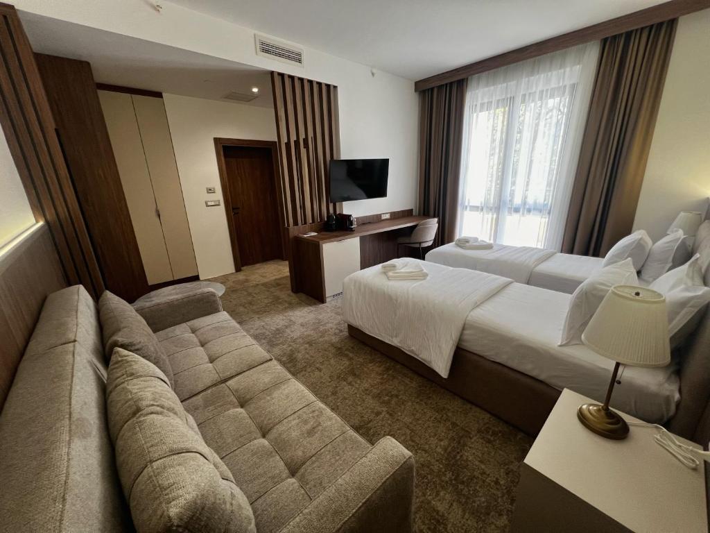 a hotel room with two beds and a couch at Hotel Onogošt in Nikšić