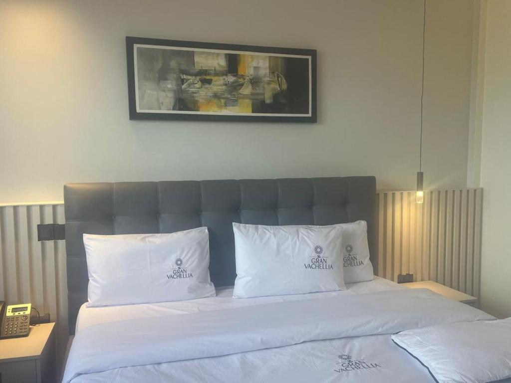 a bedroom with a bed with white sheets and pillows at Grand Vachellia Karatu in Karatu