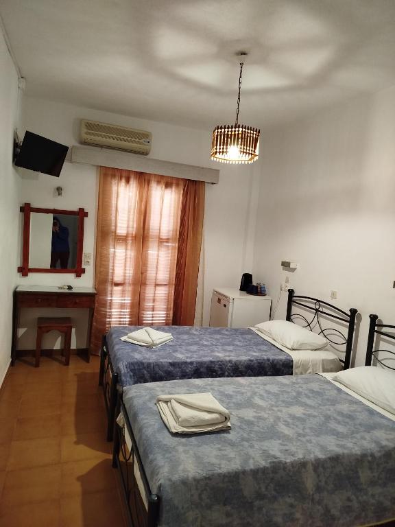 a hotel room with two beds and a desk at Christina Pension in Karterados