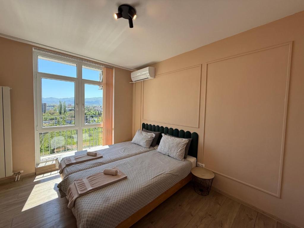 a bedroom with a bed with a large window at INTER EXPO APARTMENT in Sofia