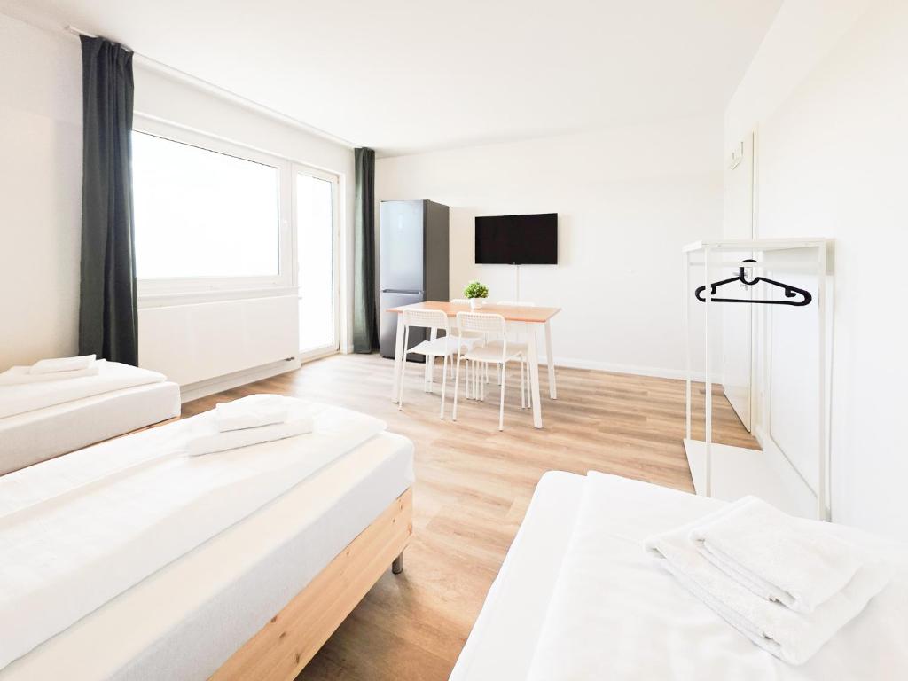a white room with two beds and a table at Tolstov Apartments - Monteurwohnungen - 2 Schlafzimmer - Küche - Balkon - Waschmaschine in Heiligenhaus