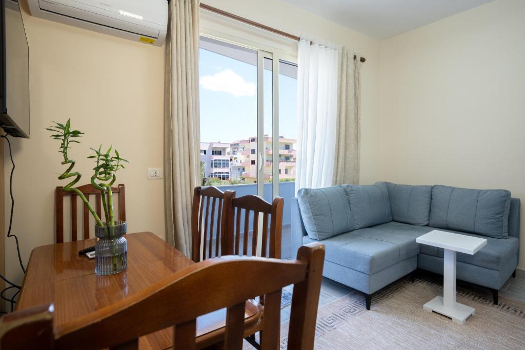 a living room with a blue couch and a table at Sea Vibe Apartment in Polisi i Vogël
