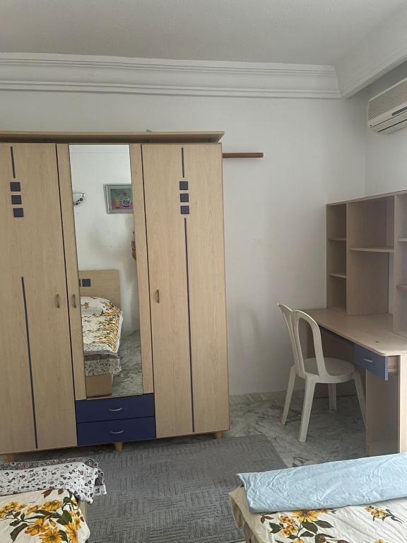 a room with a desk and a cabinet with a mirror at S1 a louer in Dar el Saïd