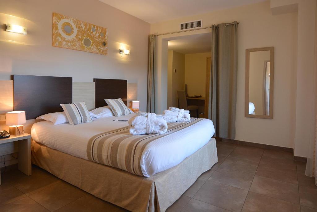 een hotelkamer met een groot bed met handdoeken erop bij Hôtel A Madonetta in Bonifacio