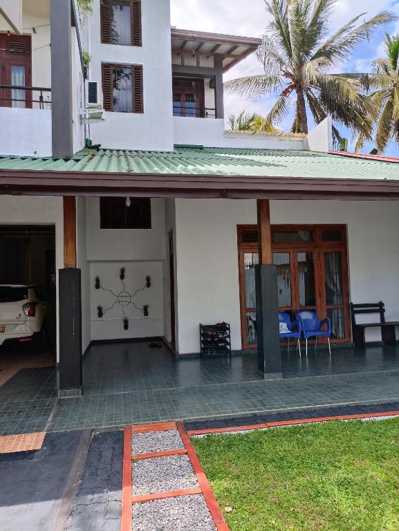 a white house with a front porch with a palm tree at LP Residence in Pannipitiya