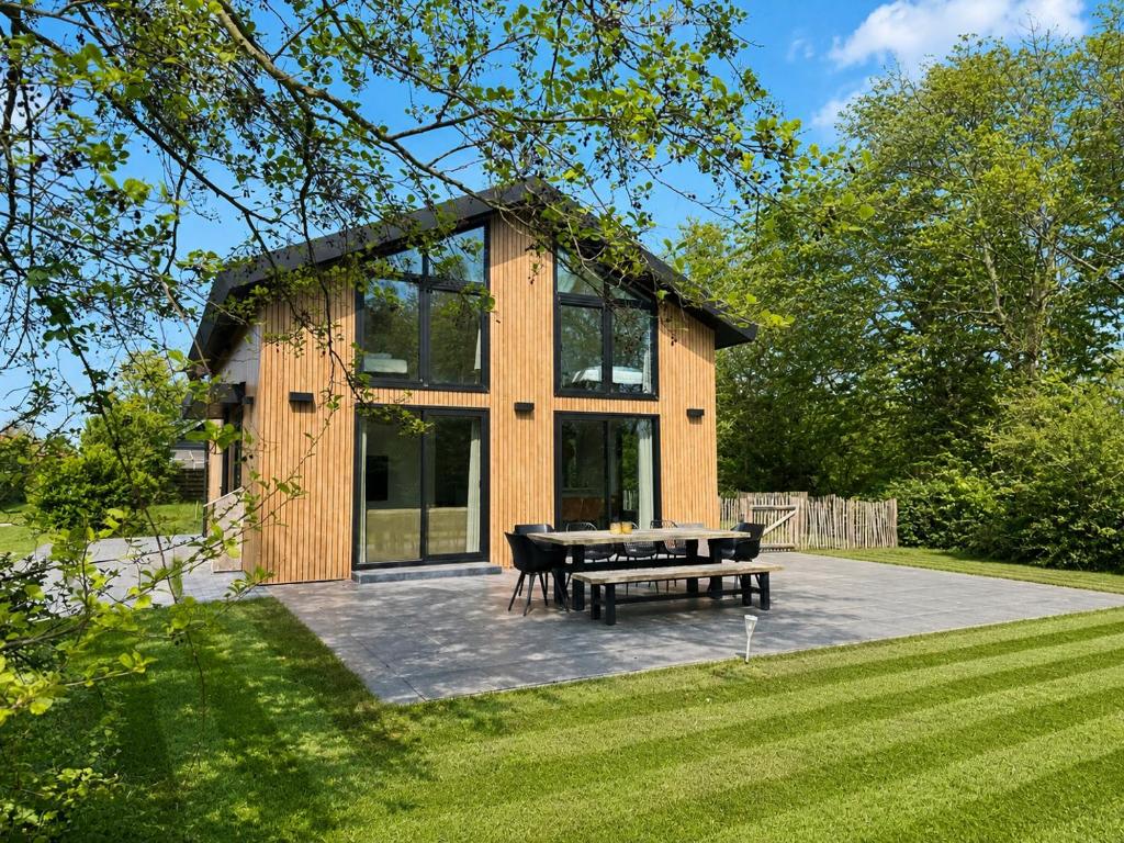 a wooden cabin with a picnic table and a bench at LouLou Beachhouse in Julianadorp