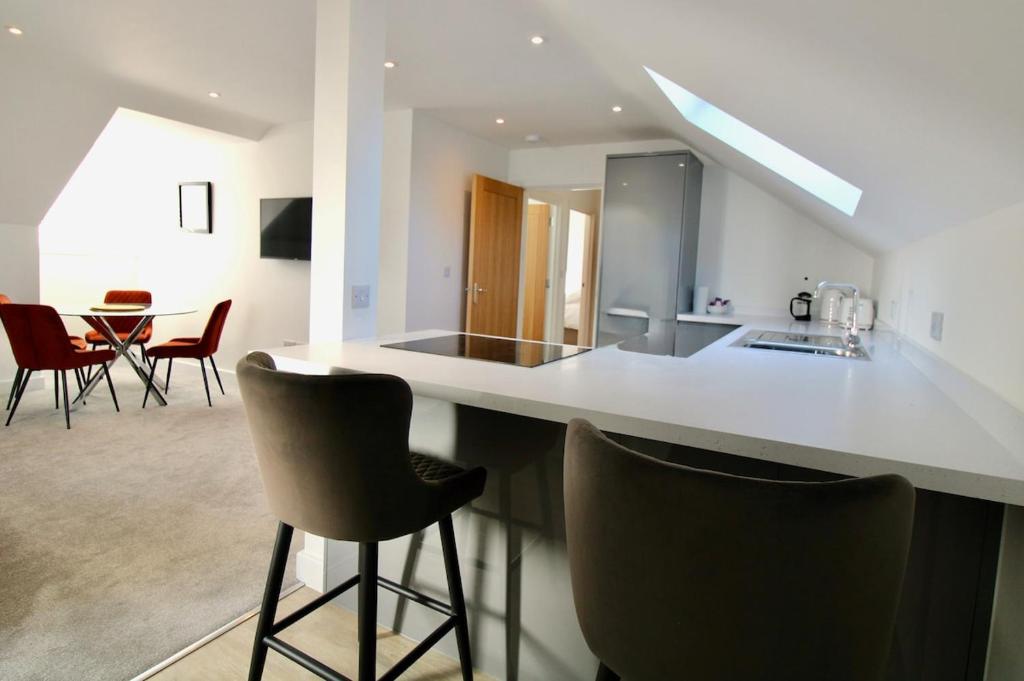a kitchen with a counter with chairs and a table at Penthouse new 2 bed 2 apartment in Basingstoke