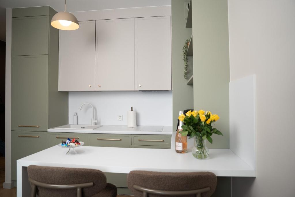a kitchen with white cabinets and a vase of flowers at Calma Apartament Moderato in Starogard Gdański