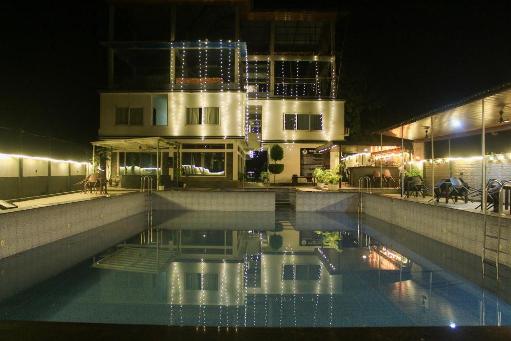 a swimming pool in front of a building at night at Peridott Inn in Jaigaon