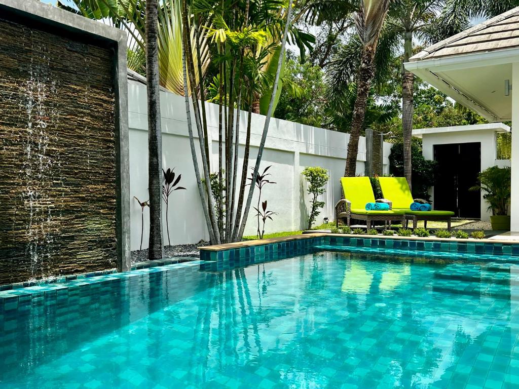 a swimming pool with two yellow chairs next to a house at Baan Tai Tara 4, Private Pool Villa by Ban Tai Beach in Ban Tai