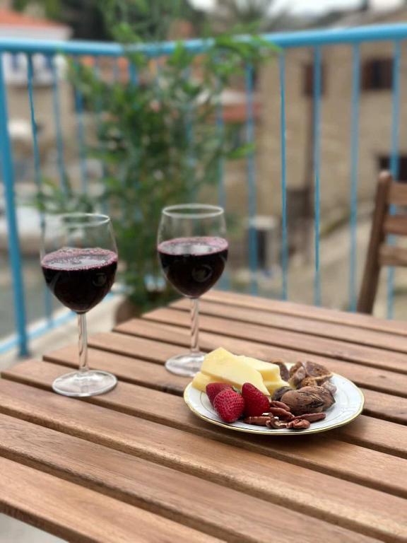 zwei Gläser Wein und ein Teller Essen auf einem Tisch in der Unterkunft Stone Nest in Tochni