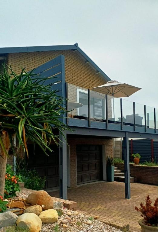 a brick house with a patio and an umbrella at Hartmel Sea Deck in Hartenbos