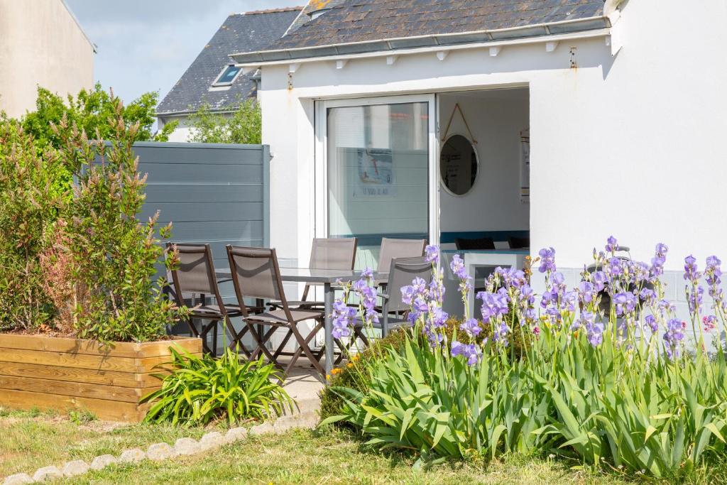 a house with chairs and purple flowers in the yard at L'escale bleue in Plomeur