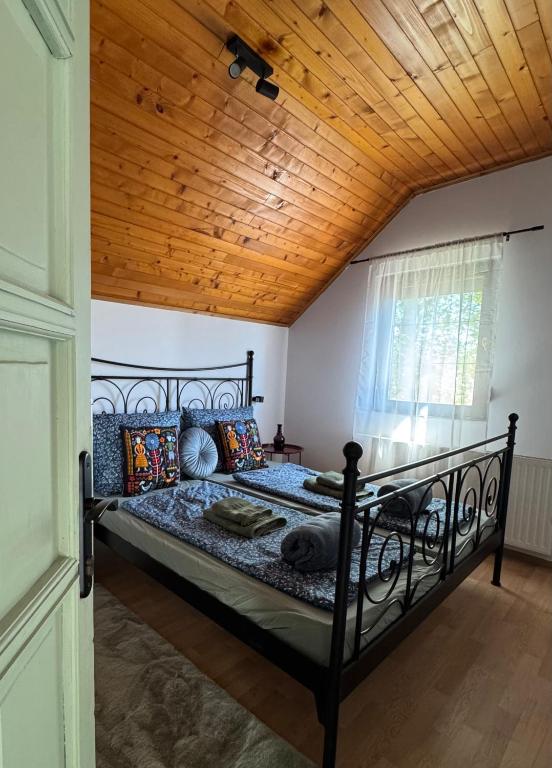 a bed in a room with a wooden ceiling at Kovács Vendégház in Harkány