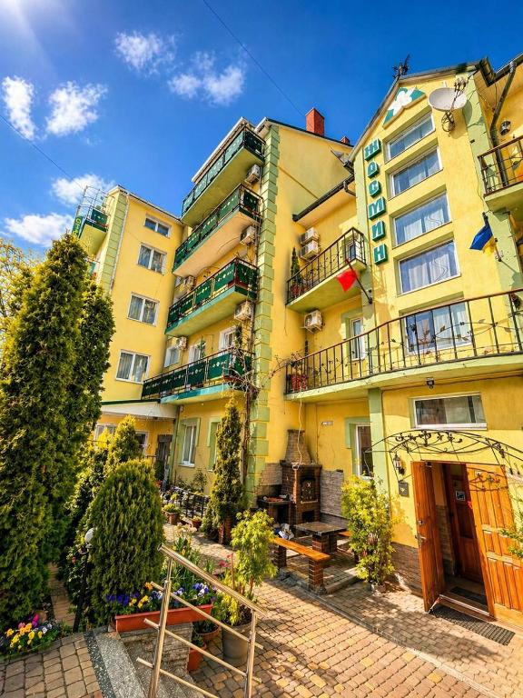 a large yellow building with benches in front of it at Hotel Jasmin All Inclusive in Truskavets
