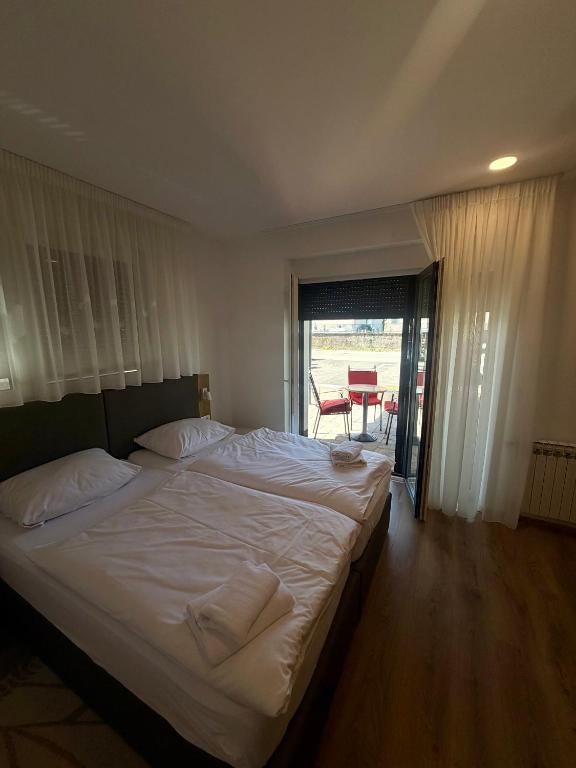 a bedroom with a large white bed with a balcony at Domus Klek in Kučinić-Selo